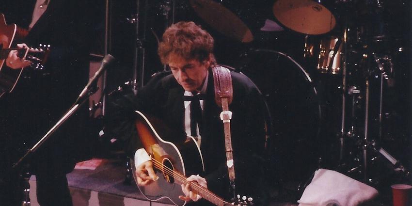 Bob Dylan performs, playing guitar and singing on stage, at the Bryce Jordan Center in 2011.